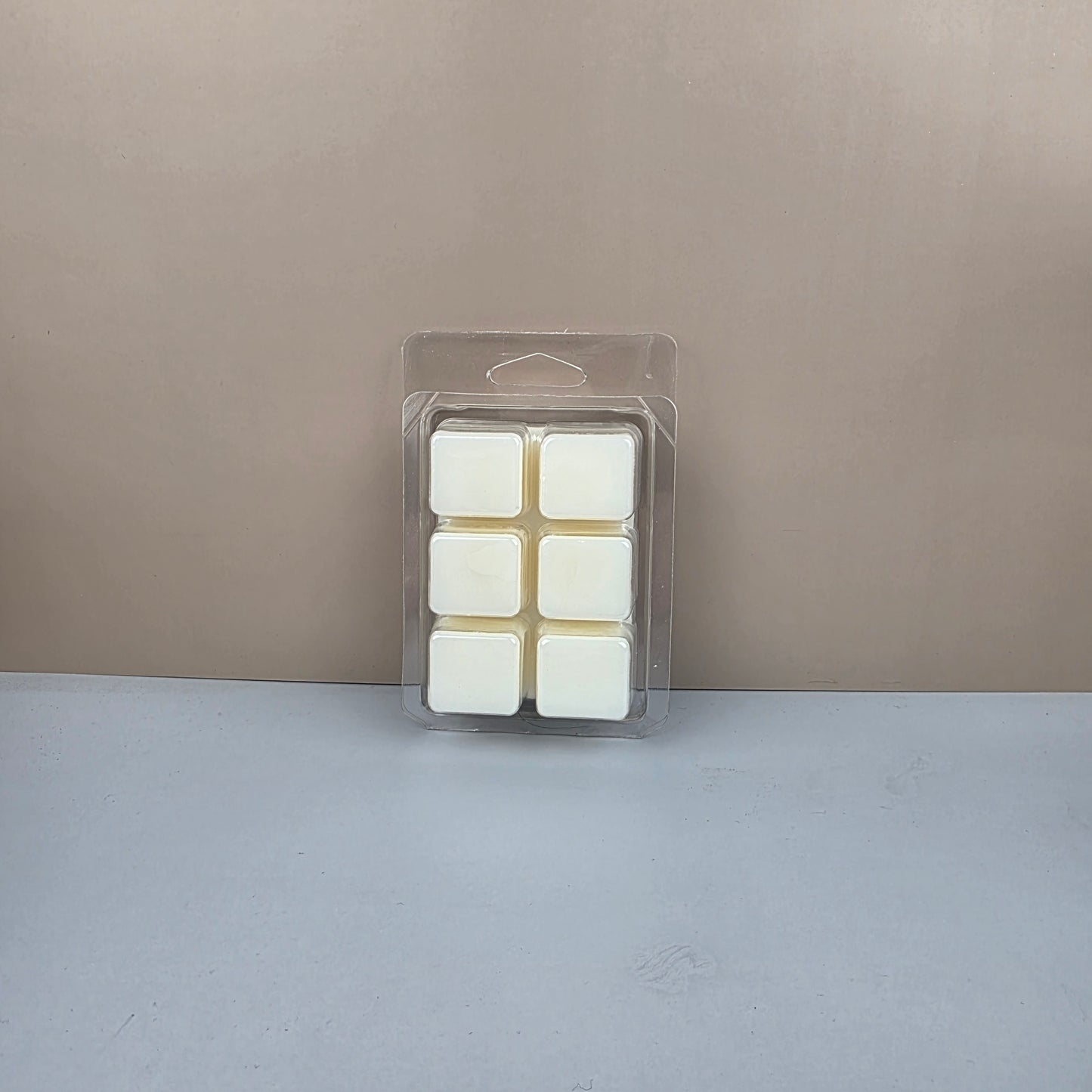 Pack of white wax melts in a clear plastic packaging against a gray background