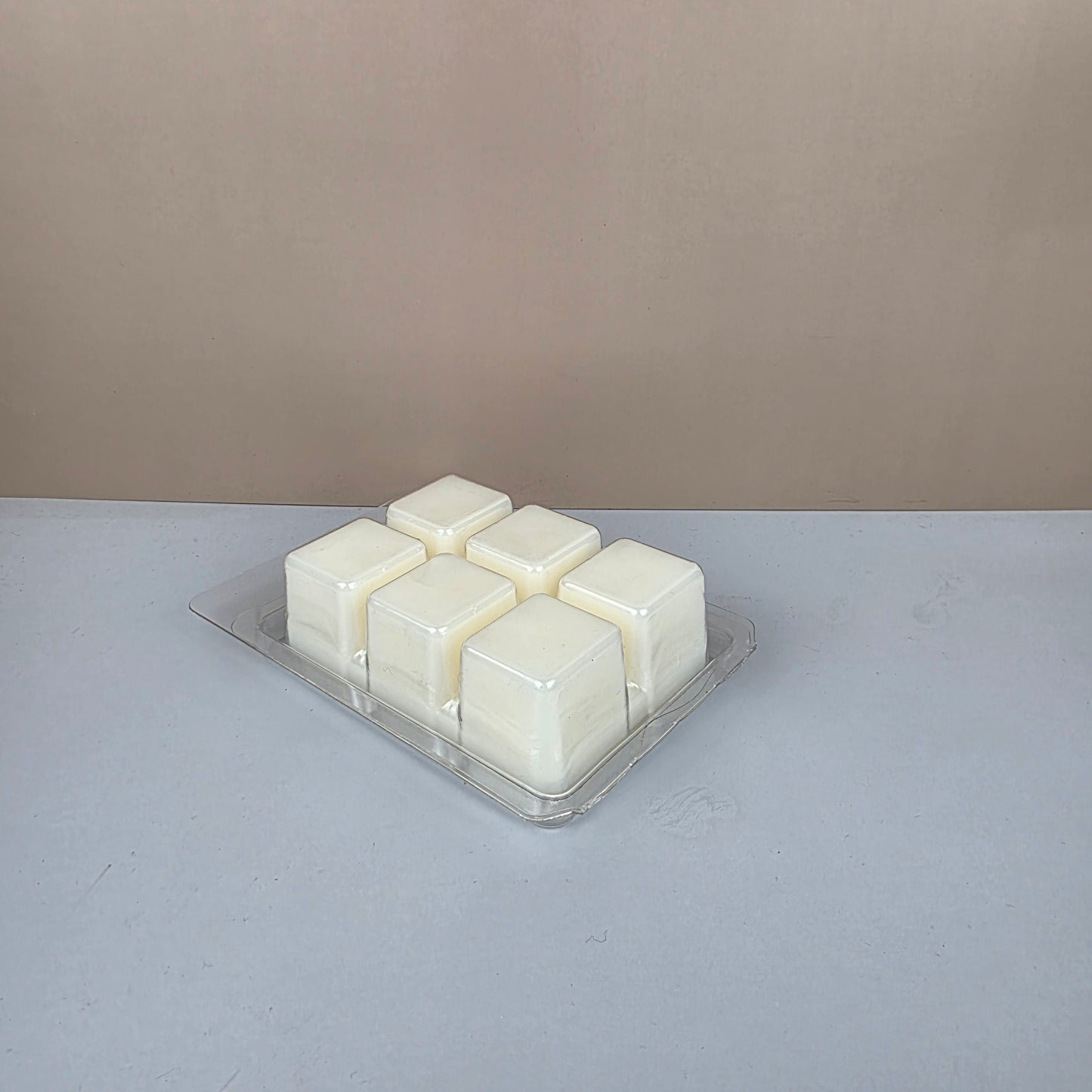 Pack of white wax melts in a clear plastic packaging against a gray background